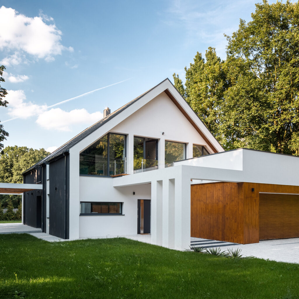 Exterior view of modern, white house with garage decorated with wood